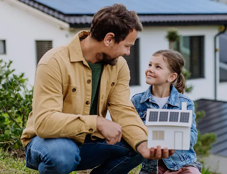 Man with child holding a model of a home